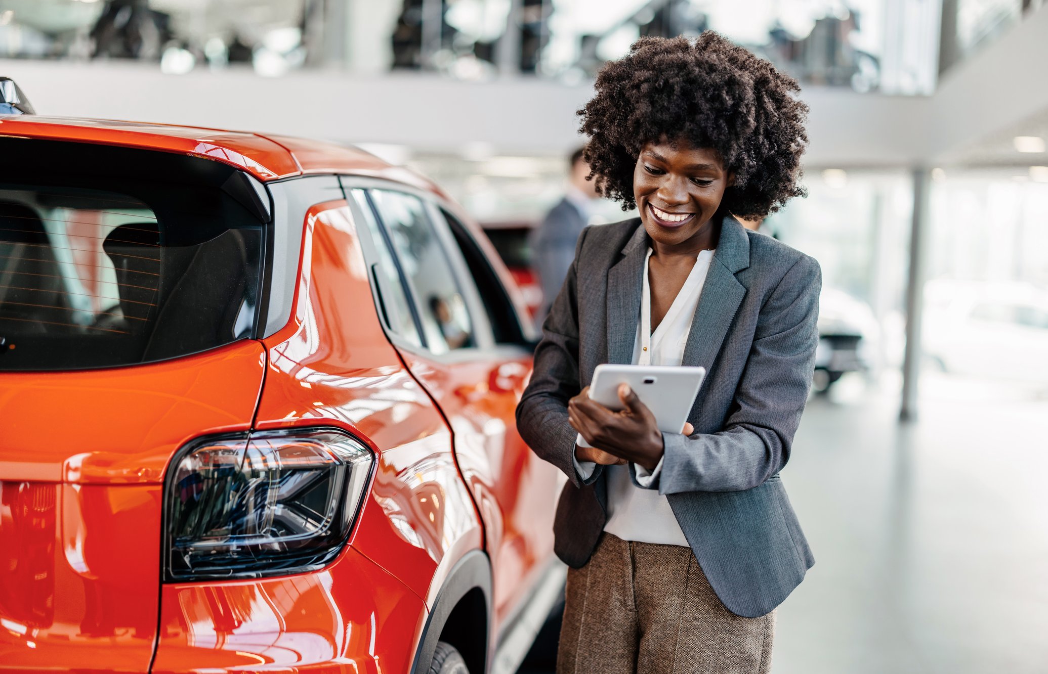 Automotive company employee next to car on her tablet